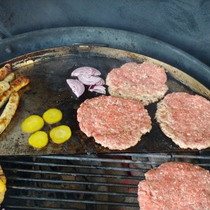 Zwiebeln und Gurken auf die Platte und Patties drauf