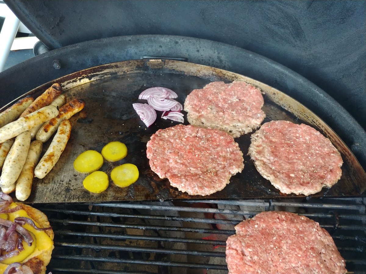 Zwiebeln und Gurken auf die Platte und Patties drauf